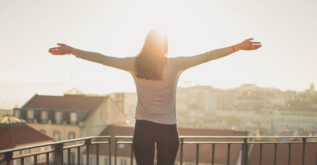 Woman practicing visualization during sunrise with open arms