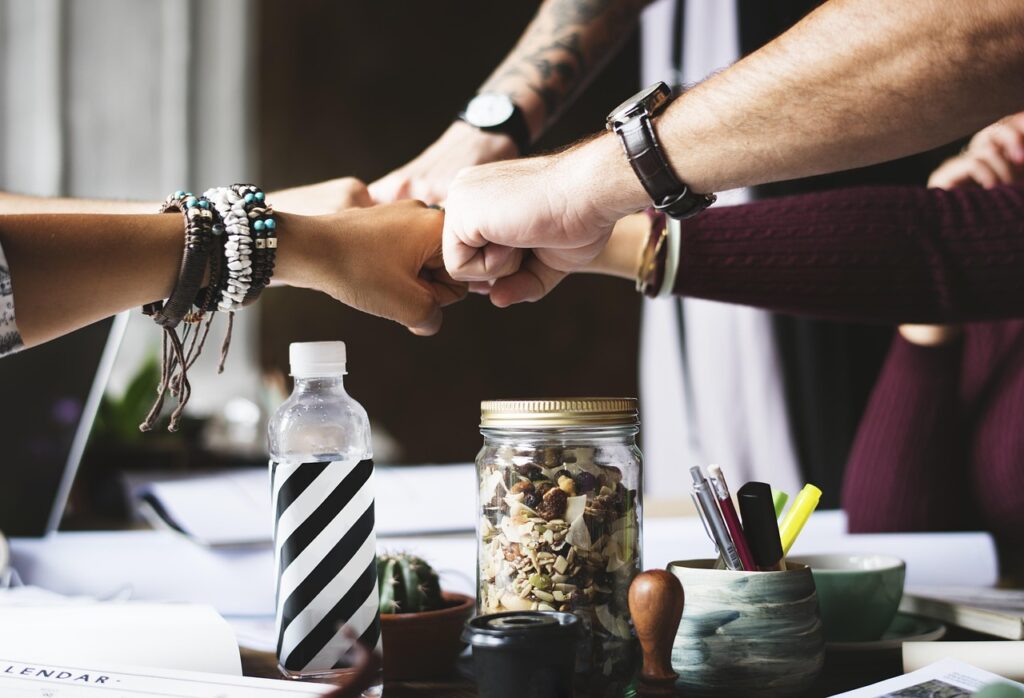 A happy team fist bumping, a symbol of how to manifest a successful business through partnership.