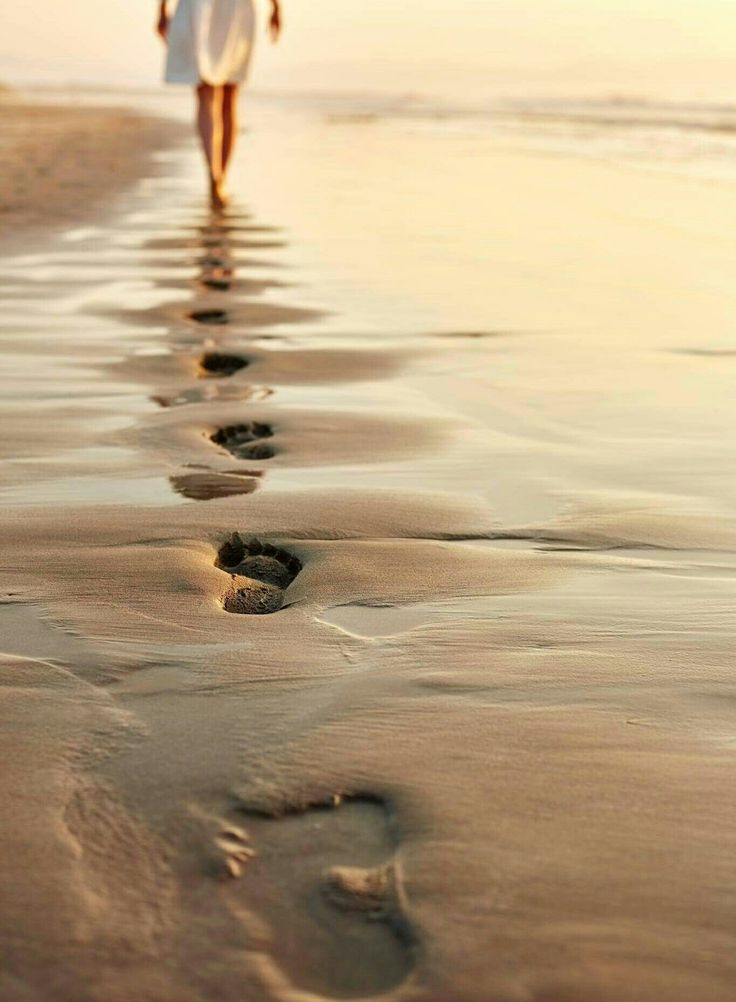 Fresh footsteps in the sand on a vast, empty beach.