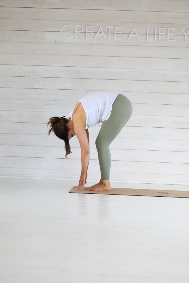 Standing forward fold with soft knees, hands toward floor